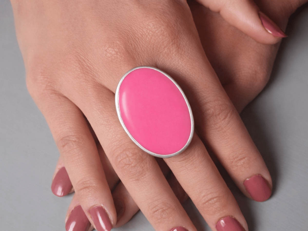A models hands wearing a large bright pink oval ring