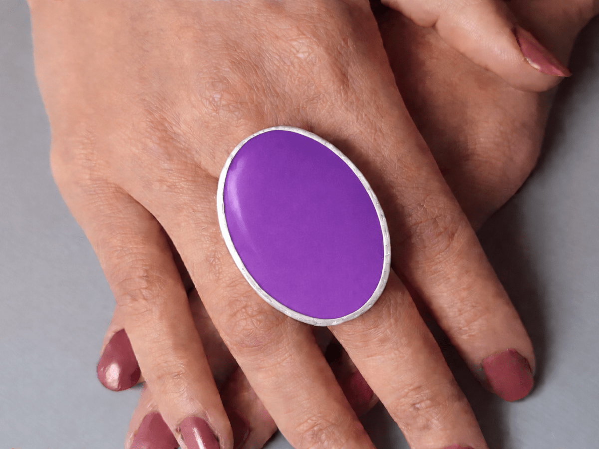 A models hands wearing a large violet oval ring