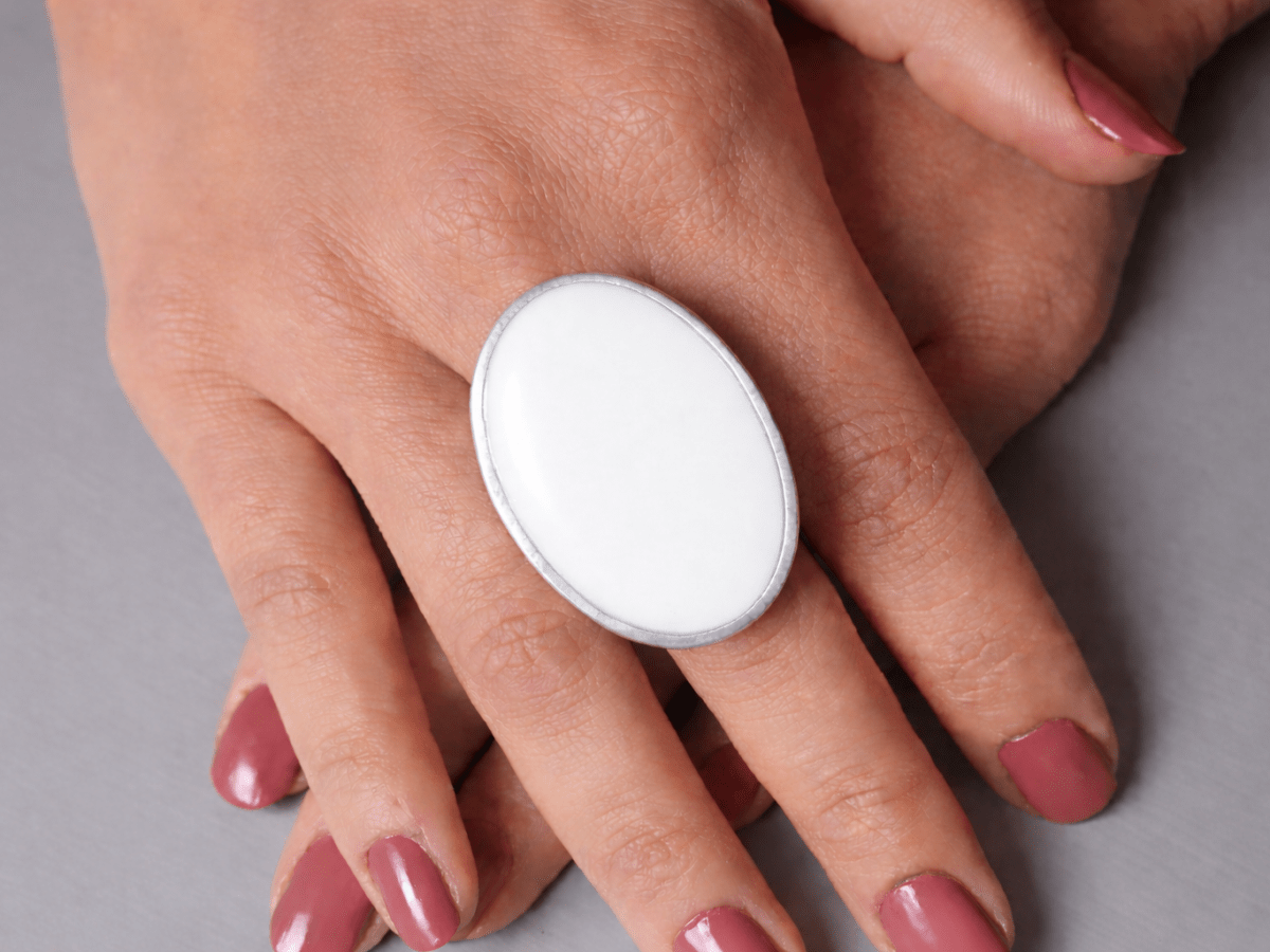 A models hands wearing a large white oval ring