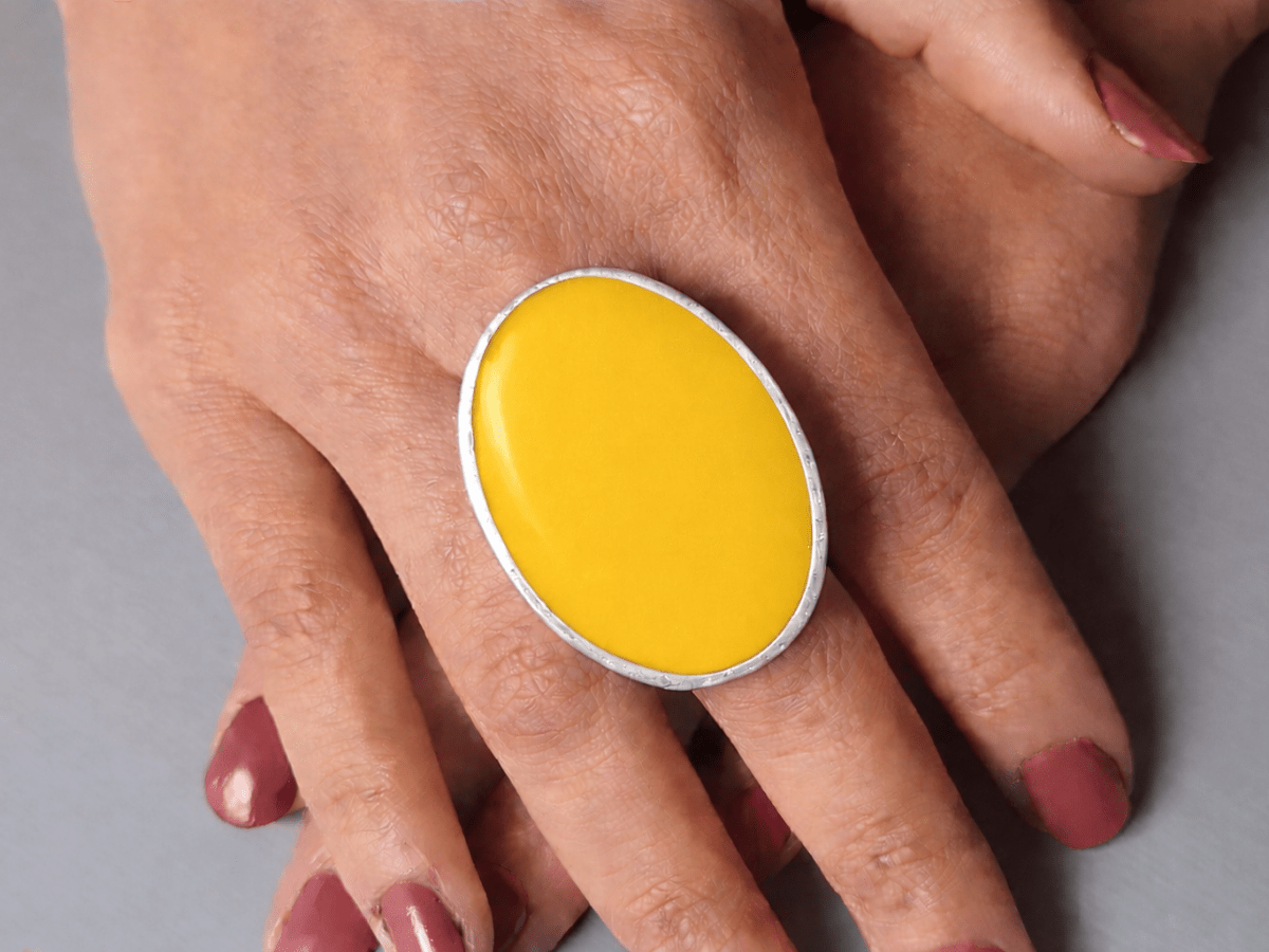 A models hands wearing a large yellow oval ring
