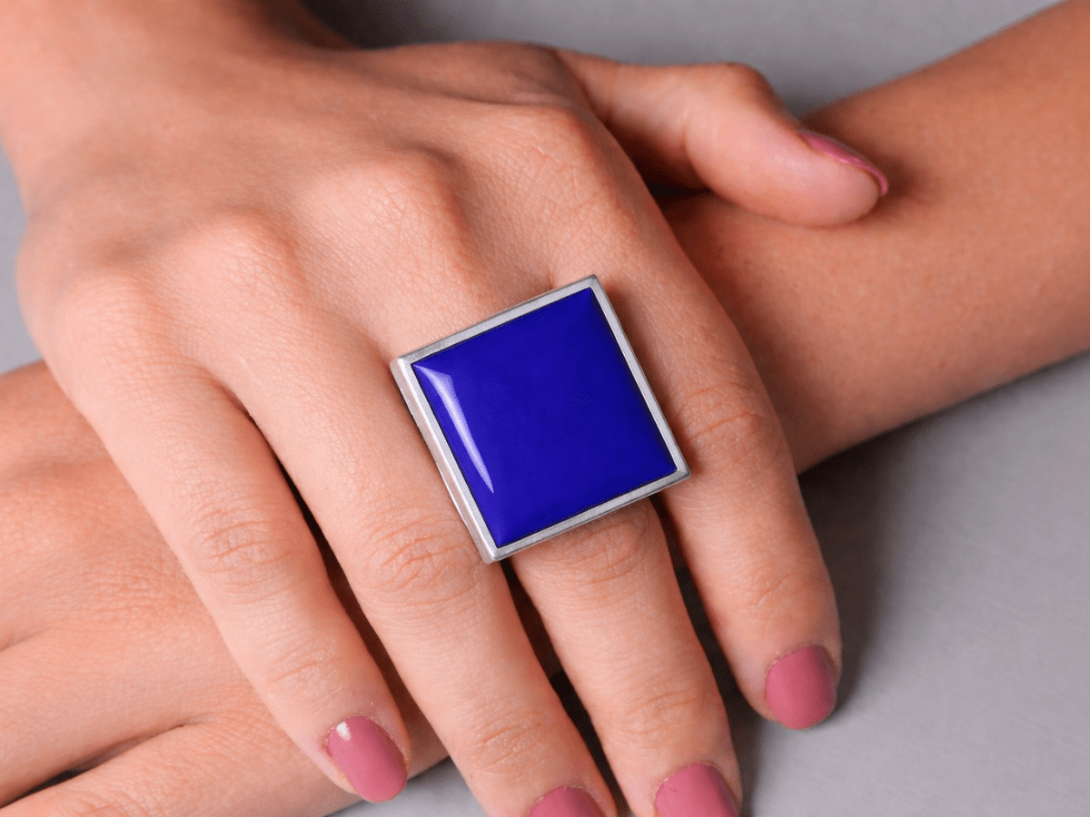 Models hands wearing a square bright blue ring