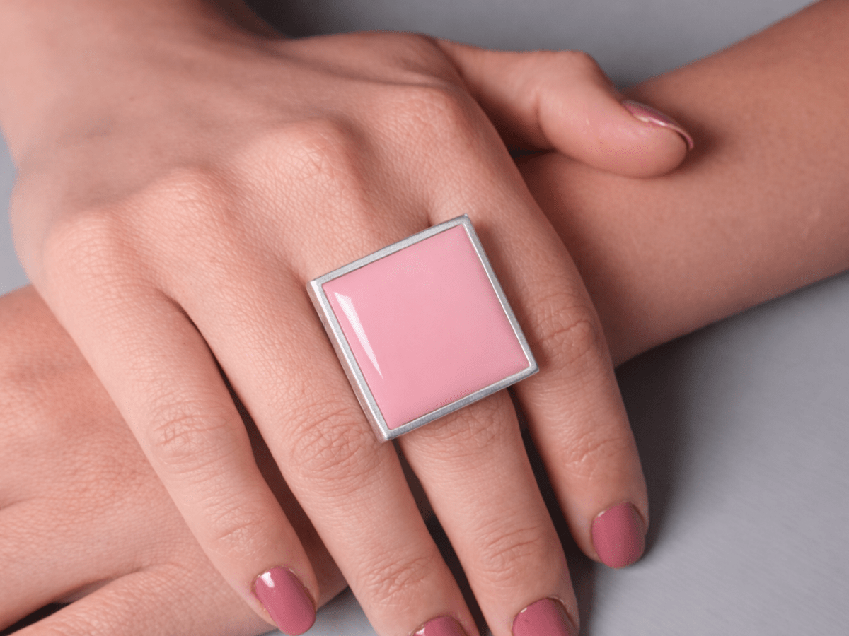 Models hands wearing a square pink ring