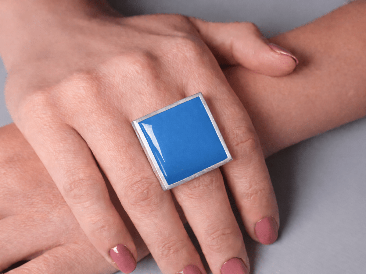 Models hands wearing a square blue ring