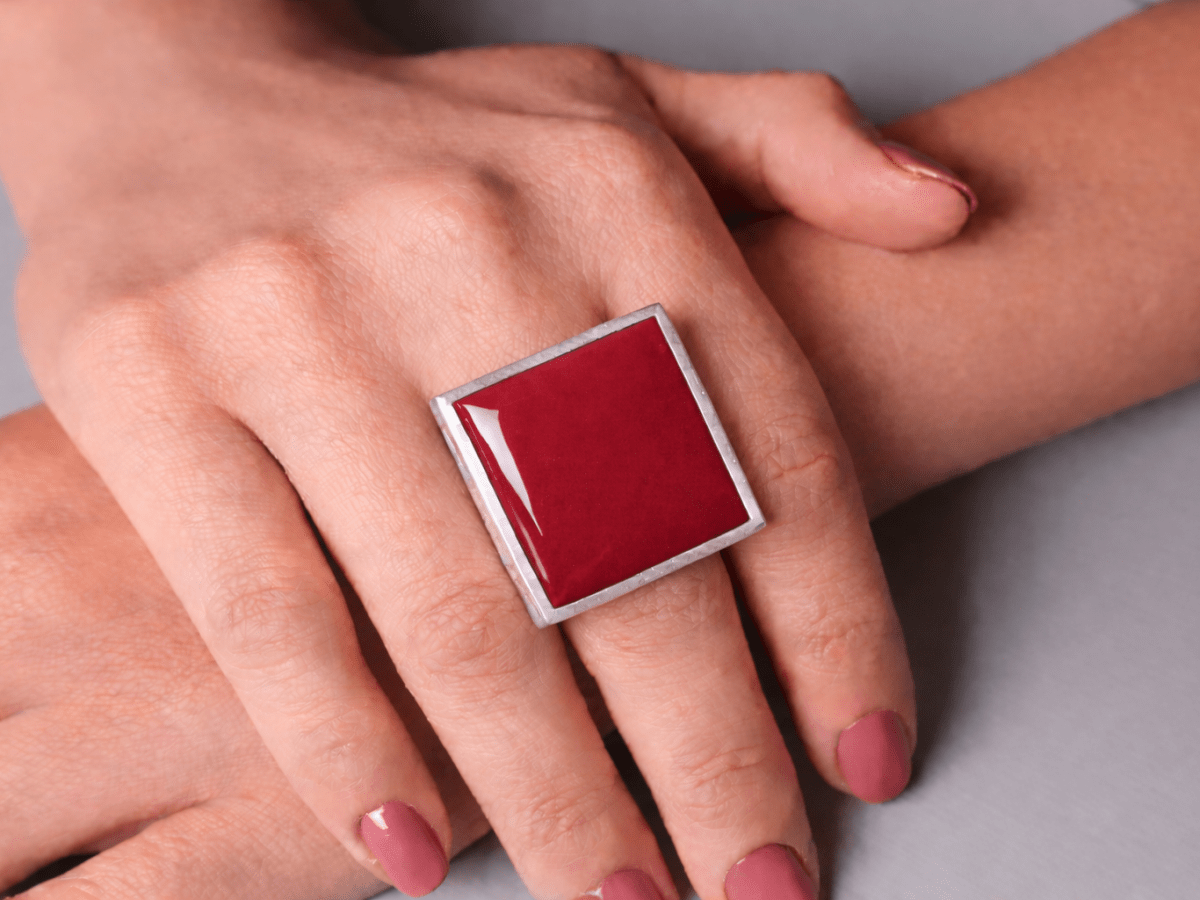 Models hands wearing a square dark red ring