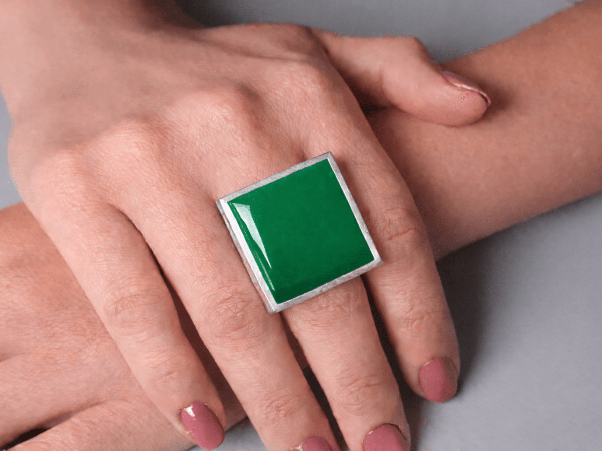 Models hands wearing a square green ring