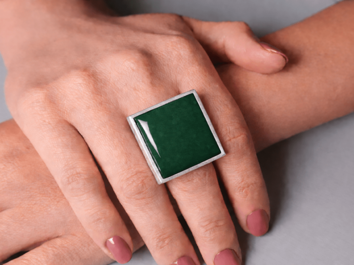 Models hands wearing a square dark green ring