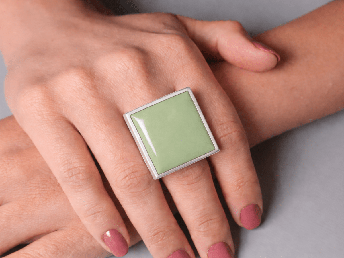 Models hands wearing a square sage green ring