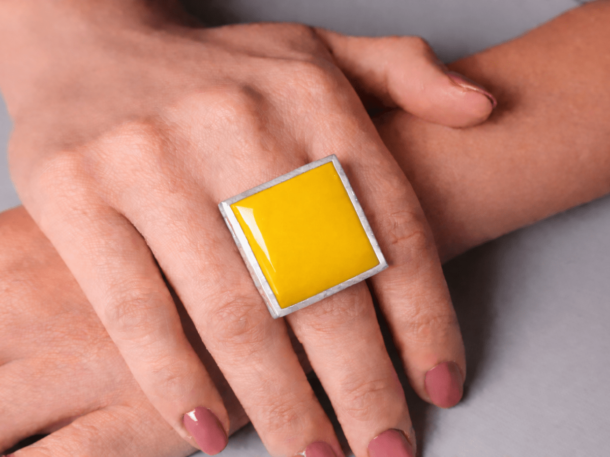 Models hands wearing a square yellow ring