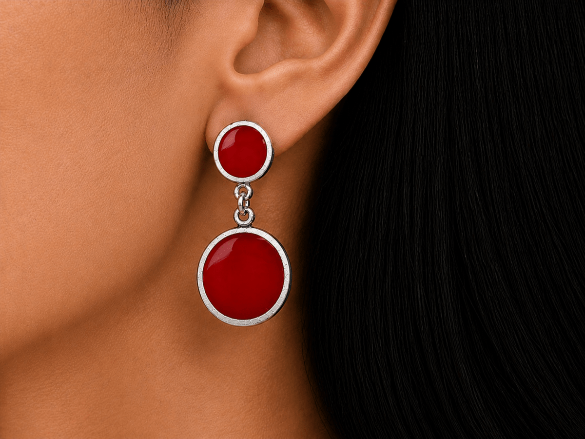 A model wearing some round dark red dangle drop earrings