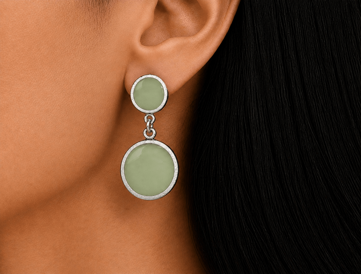 A model wearing some round sage green dangle drop earrings