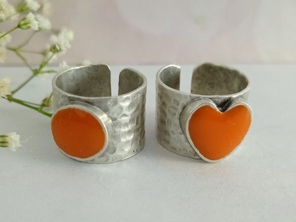 A picture of 2 bands rings, one with an orange heart one with an orange circle